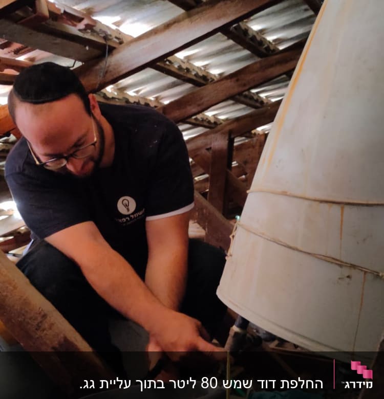 אדם מתקן דוד שמש בעליית גג עם דלי